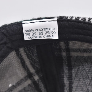 Detailed view of the plaid baseball cap interior with 100% polyester material label