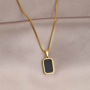 Macro detail of gold square pendant with black enamel inlay on champagne silk