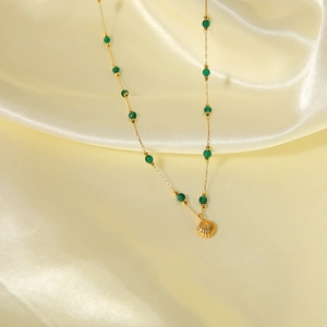 Elegant gold shell pendant necklace with green turquoise beads on silk background