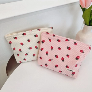 Détails de la texture velours avec motif fraise sur sacs de rangement beige et rose