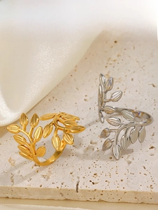 Detail of adjustable gold and silver leaf rings resting on a stone surface