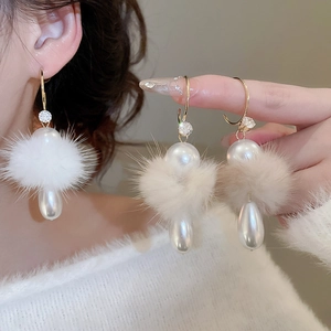 Detail of C-shaped earrings with white faux fur pom-poms and hanging teardrop pearls