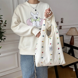 Detailed embroidery of colorful flowers and text patch on the white canvas tote bag