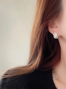 Close-up of elegant flower stud earring with pearls and zircon on model's ear