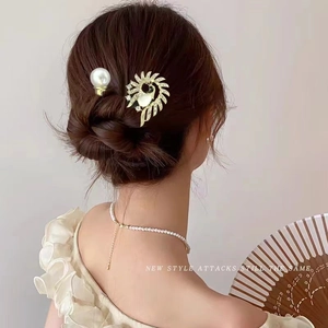 Détail d'un peigne à cheveux élégant en plumes de paon avec perles et strass sur modèle
