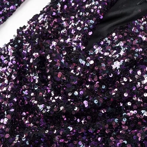 Makroaufnahme von lila und schwarzen Pailletten auf einem glitzernden Partykleid-Stoff