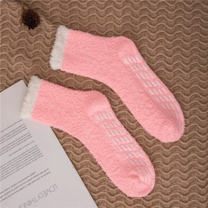Detail showing pink coral fleece socks with white cuffs and non-slip grippers on brown felt