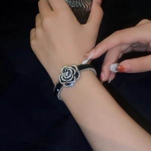 Detail of a black camellia bracelet with sparkling crystals on a model wrist