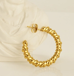 Macro detail of 18K gold-plated chunky twisted rope hoops on an artistic white bust
