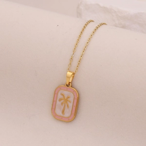 Detailed close-up of a gold palm tree pendant with pink enamel border on textured surface