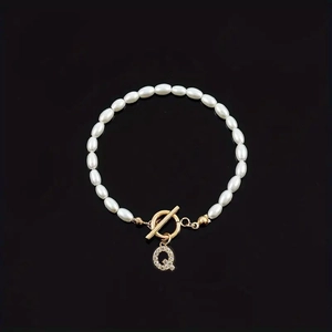 Pearl bracelet featuring a gold OT buckle and sparkling diamond-set letter Q pendant