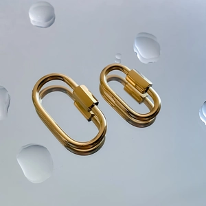 Macro detail of gold screw lock carabiner clasps on a reflective water drop surface