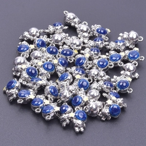 Macro shot of silver astronaut bear pendants with blue glitter belly on gray surface