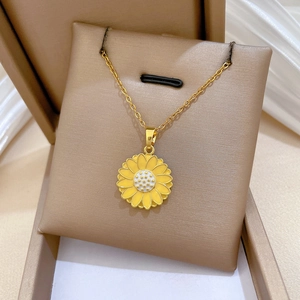 Close-up of golden sunflower pendant necklace with yellow enamel petals and cross chain