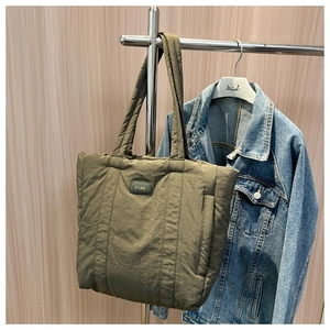 Detail of soft quilted olive nylon tote bag with stitched texture and brand patch