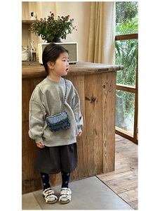 Close-up of a stylish denim chain crossbody bag paired with a gray toddler outfit