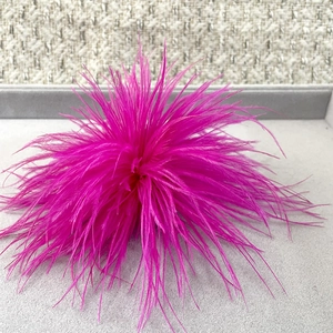 Detailed view of magenta ostrich feather brooch with soft texture on display tray