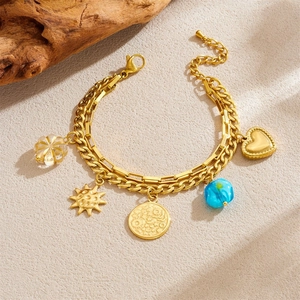 Bohemian gold double-layer bracelet with heart and coin charms on a sandy background