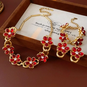 Macro detail of vintage gold flower jewelry set with red glass and white crystals