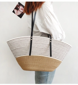 Detail of striped woven tote bag featuring black leather straps and gold rivet accents