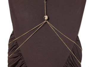 Close-up of golden chain necklace with polished metal bead on brown pleated dress