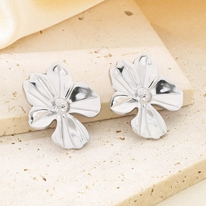 Macro shot of silver floral earrings with pearl centers on beige silk fabric