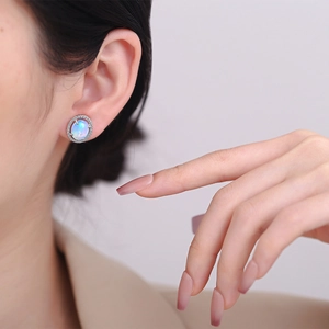 Oval opal stud earrings with halo cubic zirconia setting shown on a model