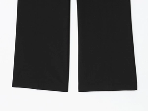 Gros plan de l'ourlet du pantalon noir montrant la texture du tissu textile de qualité