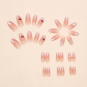 Detail view of almond cat eye press-on nails with pink gradient and 3D red bow accents