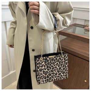 Close-up of leopard print handbag featuring gold chain strap and black leather handle