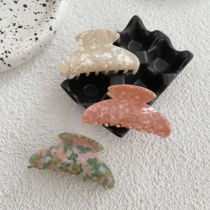 Gros plan de trois pinces à cheveux en acétate aux motifs marbrés et floraux sur un plateau