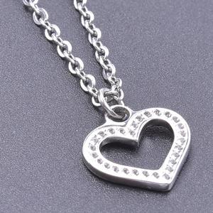 Macro shot of silver heart pendant with sparkling crystals on a textured dark background