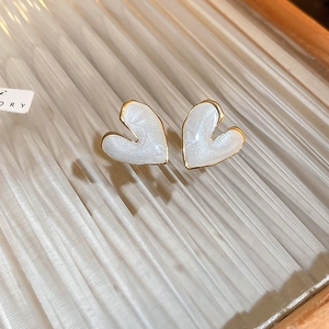 Close-up of heart-shaped gold studs with white pearlescent enamel on ribbed glass