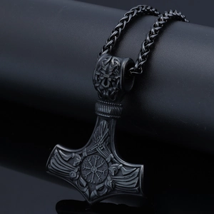 Detail of black Viking Mjölnir pendant with intricate rune engravings and raven motifs