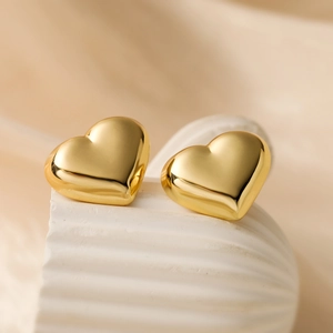 Minimalist gold-plated heart stud earrings displayed on a white decorative shell