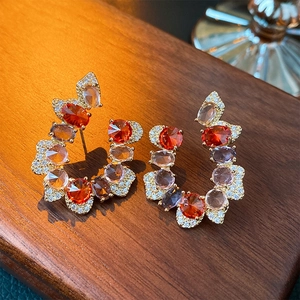 Detailed close-up of C-shaped drop earrings with orange and purple cubic zirconia