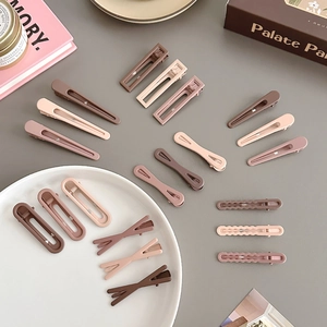 Various coffee-toned matte seamless hair clips arranged on a stylish grey desktop