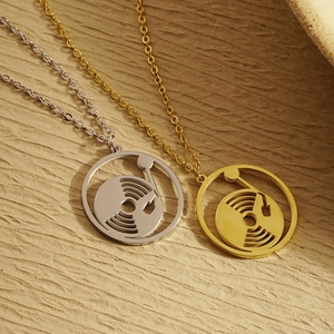 Vintage record player pendant necklace in gold and silver finishes on textured background