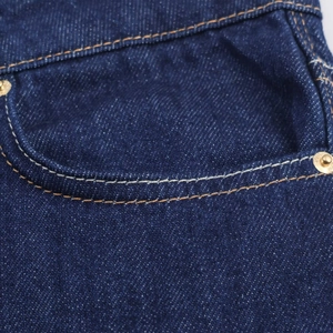 Détails de la texture du denim bleu foncé et rivets métalliques renforcés sur le jean