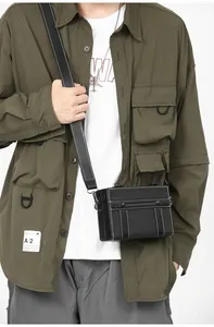 Dettaglio di una borsa a tracolla box nera con cuciture bianche a contrasto su un modello