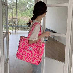 Close-up of pink leopard print canvas tote bag with 'You need this one' label on handle