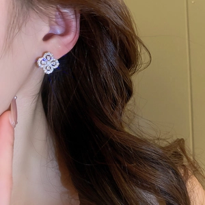 Close-up of sparkling silver hollow flower stud earrings with zircons on a model