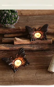 Détail de bougeoirs papillon en fonte noire vintage sur une surface en bois rustique