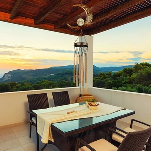 Solar moon wind chime with bronze metal tubes and crystal ball light against sunset sea view