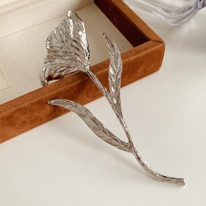 Close-up of silver metal flower brooch with wrinkled texture on brown velvet jewelry box
