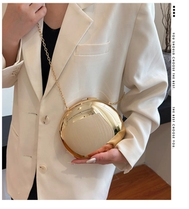 Close-up of golden spherical mirror bag with delicate chain strap for evening wear