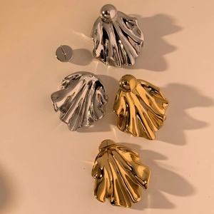 Detail of shell-shaped wrinkled earrings in gold and silver finish with mirror polish