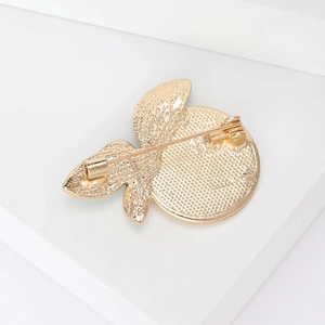 Back view of a gold lemon brooch showing detailed metal texture and safety pin clasp