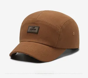 Dettaglio di un cappello camp a cinque pannelli marrone con toppa in pelle e occhielli