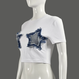 Detail of white crop top featuring blue denim star patches with frayed tassel edges